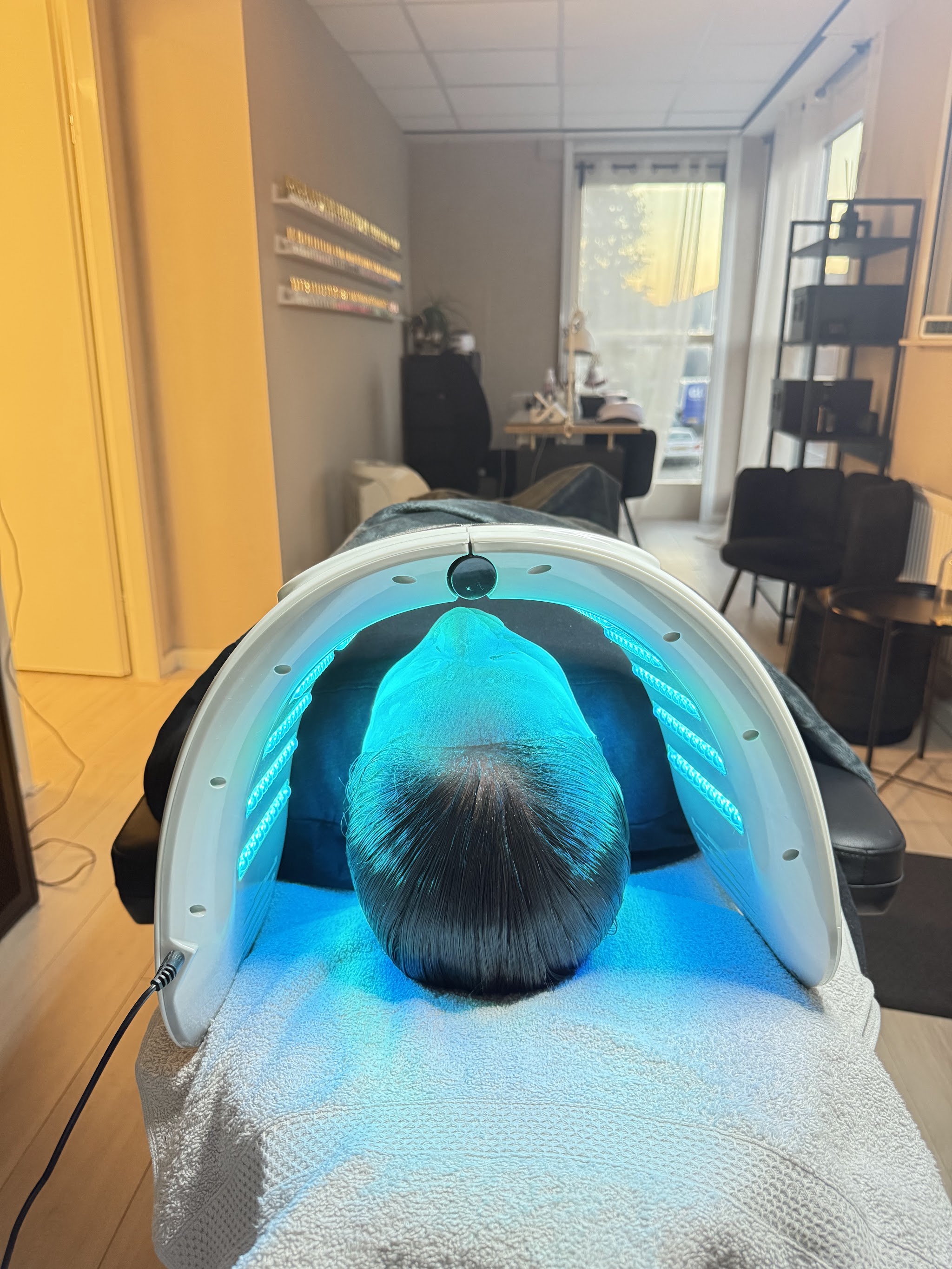 Een klant onder het LED-masker met blauw licht in de behandelkamer
